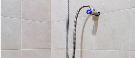 A shower with a handheld showerhead and a flexible hose, mounted on a tiled wall.