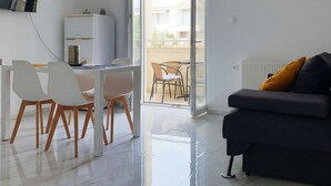Ein modernes Wohnzimmer mit einer Couch, einem Esstisch mit Stühlen und einem Balkon mit Gartenmöbeln.