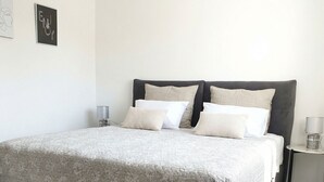 Ein Schlafzimmer mit einem großen Bett, zwei Nachttischen und einem Wandbild.