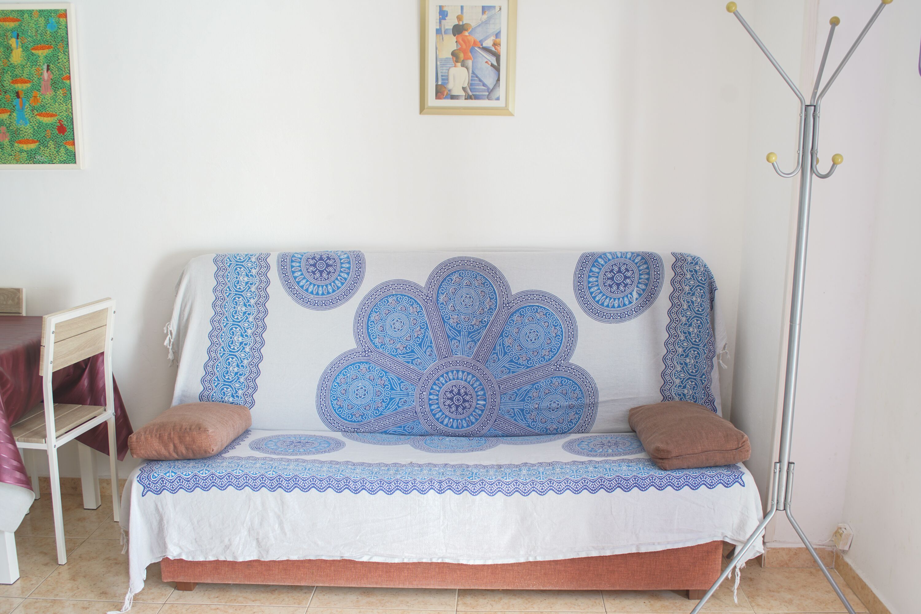 Un canapé blanc agrémenté de coussins à motifs bleus et bruns, un lampadaire et un tableau encadré accroché au mur.