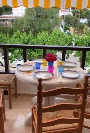 A round table set for two with plates, glasses, and a vase of flowers. - Manila Playa Pp2 PET (Alcocéber)