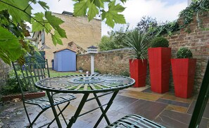 Enjoy al fresco dining on the patio, surrounded by lush greenery and a charming brick wall.