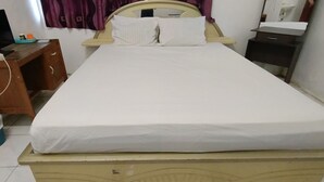 A single bed with a wooden frame, a bedside table with a lamp, a small desk with a computer, and a trash bin. - SPOT ON 92338 Karin Kost (Karang Intan)