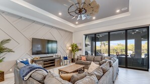A modern living room with a large sectional sofa, a flat-screen TV, and a ceiling fan. - Games Room | Theater Room | Kids Bunk Themed Bedrooms | Pool with Golf Course Views (Kissimmee)