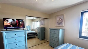 Un dormitorio con cama, cómoda, televisión, armario y ventana.