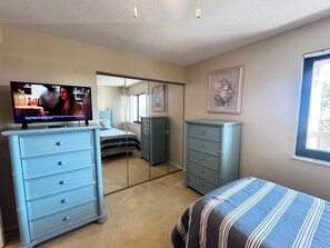 A bedroom with a bed, a dresser, a TV, a wardrobe, and a window. - BT 3942 Pond View Condo-Welcome to Paradise (Fort Pierce)