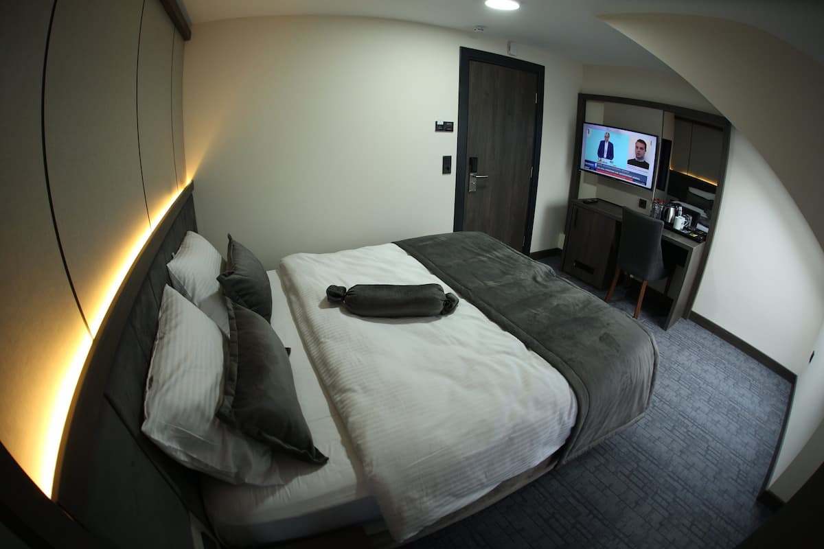 A hotel room with a bed, a TV, a desk, and a chair.