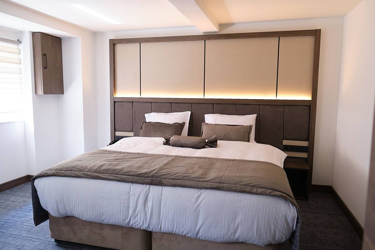 A neatly made bed with a headboard, a bedside table, and a wall-mounted cabinet.