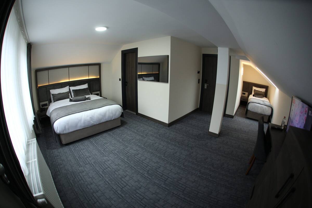 A hotel room with a large bed, a bedside table, a mirror, and a small seating area.