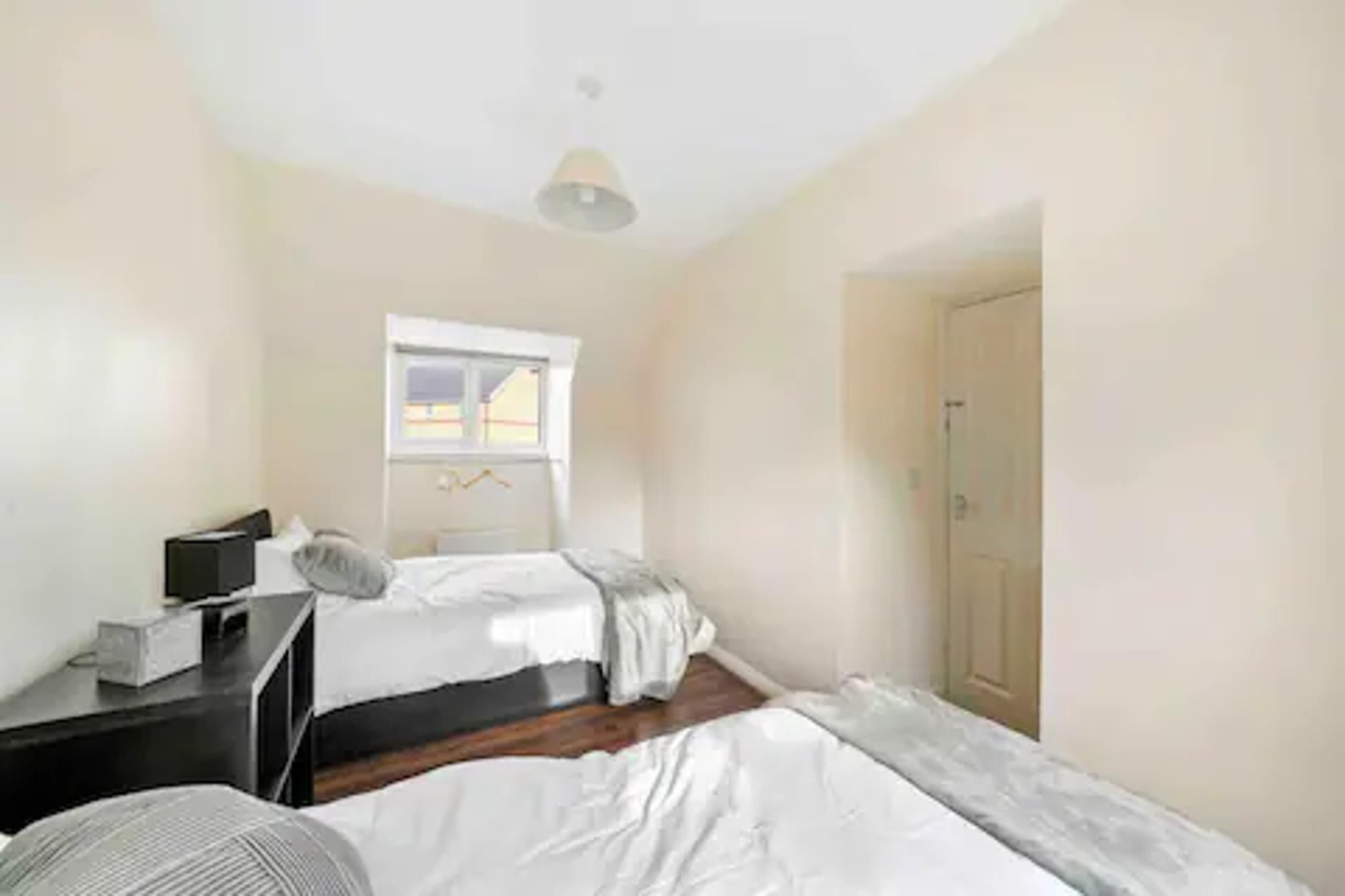A small, clean room with two beds, a desk, and a window.