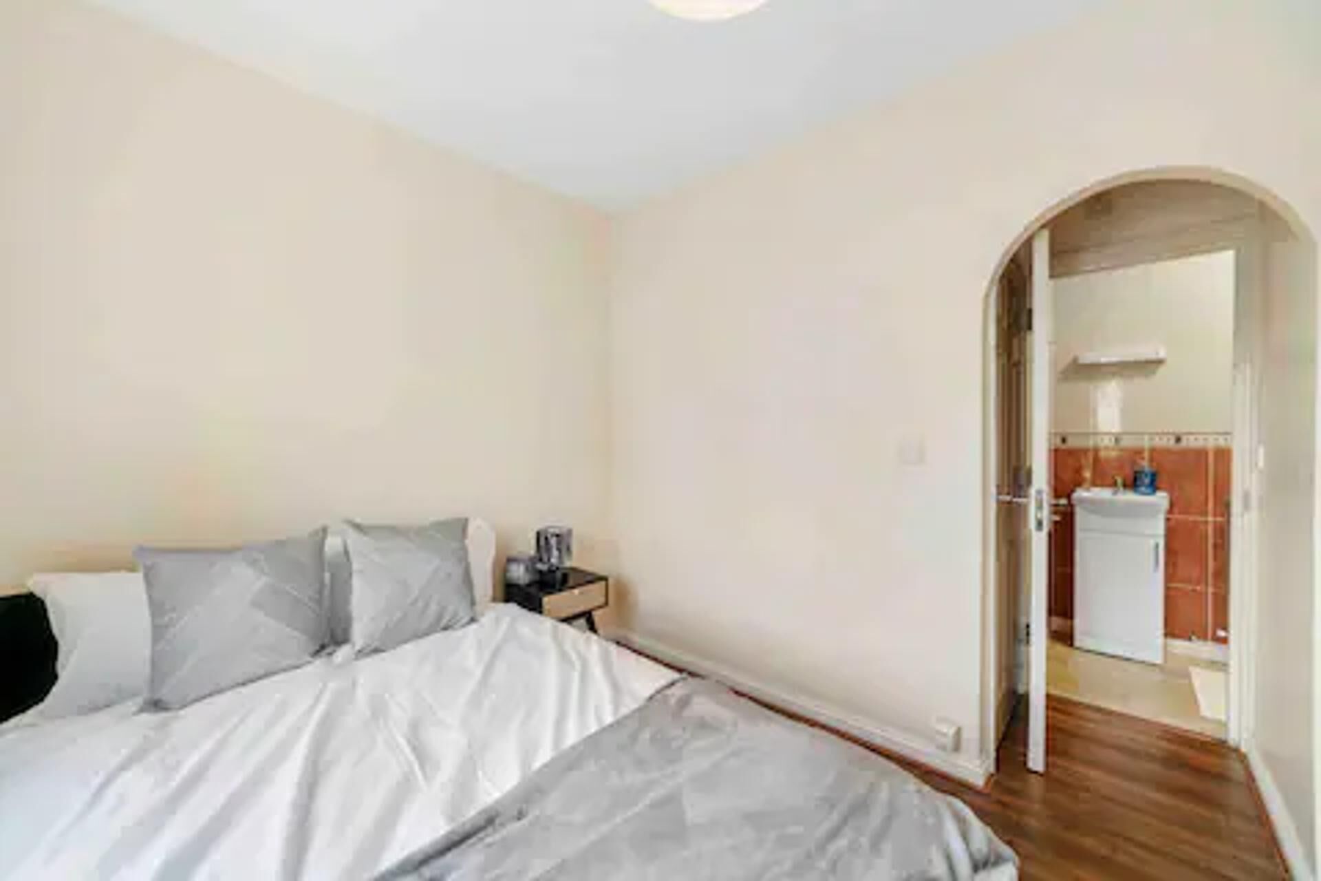 A bedroom with a bed, a nightstand, and a bathroom visible through an archway.