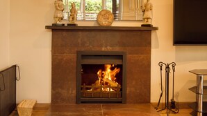 Une cheminée avec un feu, un miroir au-dessus et une statue sur le manteau.