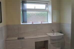 Ein Badezimmer mit Fenster, Waschbecken und Spiegel.