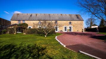 A stone building with a sloped roof, a paved driveway, and a well-maintained lawn.
