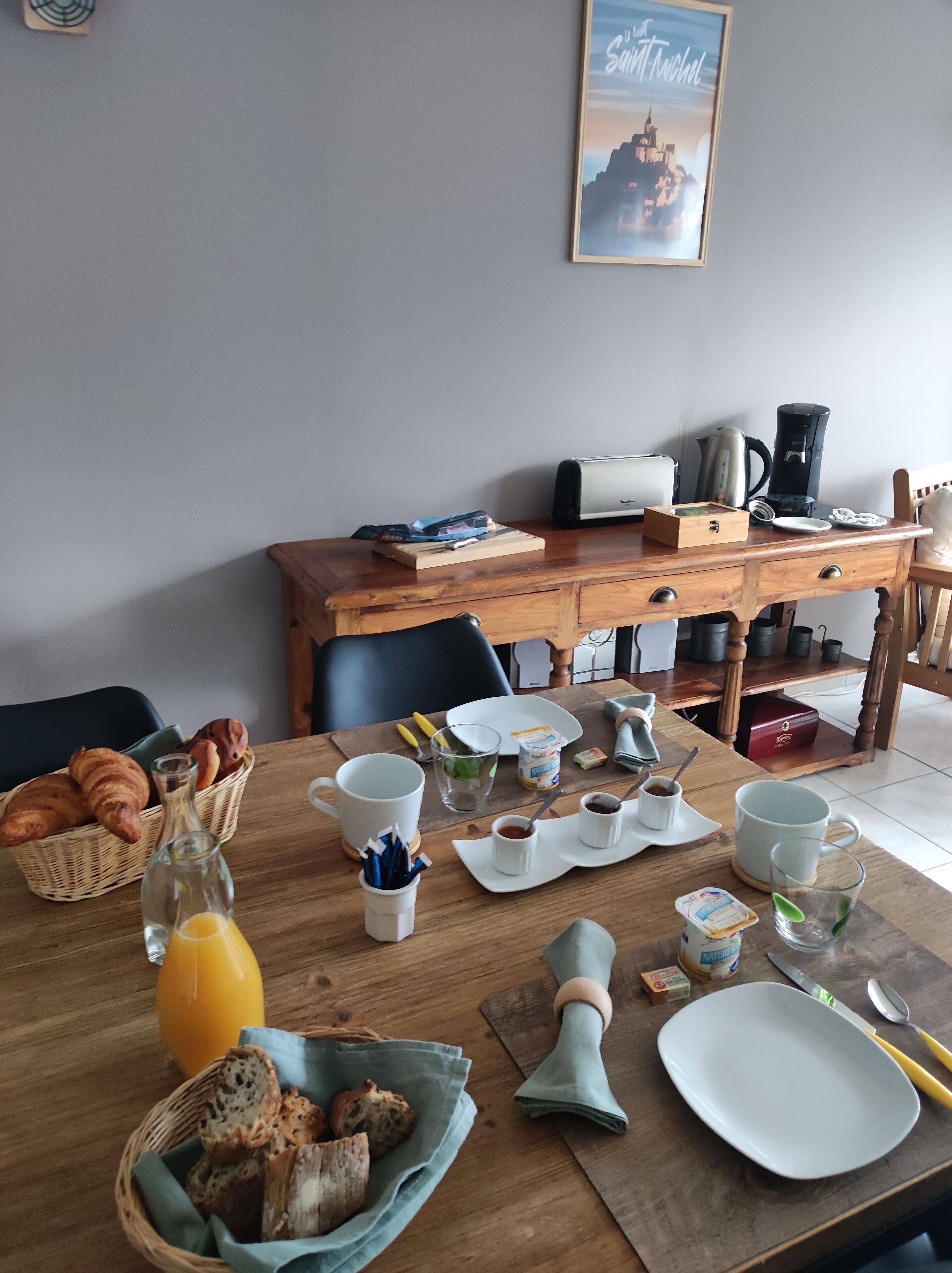 A breakfast table with croissants, bread, juice, and coffee.