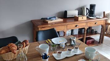 A breakfast table with croissants, bread, juice, and coffee.
