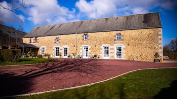 A large stone building with a red driveway, multiple windows, and a flat roof.