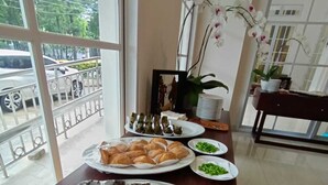 A dining area with a large table set with various dishes, including pastries and a chocolate dessert. - Giia Sanno Menteng (Jakarta)