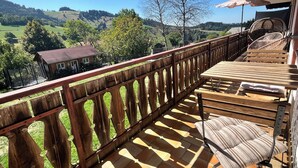 A wooden balcony with a view of a green landscape, a wooden table, and a chair. - Recreation resort for Black Forest fans (Horben)