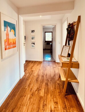 Un couloir avec un plancher en bois, un panneau d’accueil encadré et un téléviseur en arrière-plan.