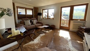 A spacious living room with a brown leather sofa, a coffee table, and a large window offering a view of the countryside. - Recreation resort for Black Forest fans (Horben)