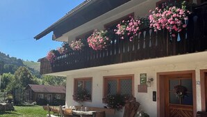 A two-story building with a balcony adorned with pink flowers, a wooden bench, and a table outside. - Recreation resort for Black Forest fans (Horben)