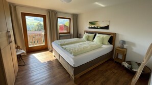 A bedroom with a bed, a nightstand, a lamp, a window with curtains, and a view of the outdoors. - Recreation resort for Black Forest fans (Horben)