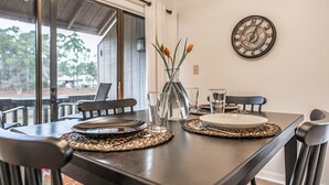 A dining table set with plates, glasses, and a vase with flowers. - Long Drive On No. 5 - 1BR Condo w/ GREAT Golf Views, Minutes From Clubhouse (Pinehurst)