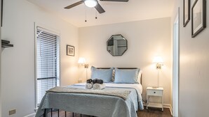 A bedroom with a bed, two bedside tables, a ceiling fan, and a window with blinds. - Long Drive On No. 5 - 1BR Condo w/ GREAT Golf Views, Minutes From Clubhouse (Pinehurst)