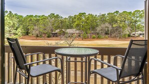 A balcony with two chairs and a table, overlooking a wooded area with houses. - Long Drive On No. 5 - 1BR Condo w/ GREAT Golf Views, Minutes From Clubhouse (Pinehurst)