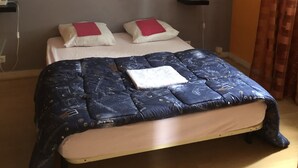 Quarto com uma cama, duas mesas de cabeceira, um quadro na parede e uma cortina.
