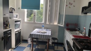 Uma cozinha compacta com uma toalha de mesa listrada, uma garrafa de água e uma chaleira no balcão.