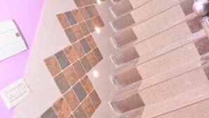 A staircase with a patterned tile design, a door, and a light switch on the wall. - Hotel Sahu Inn Ayodhya (Faizabad)