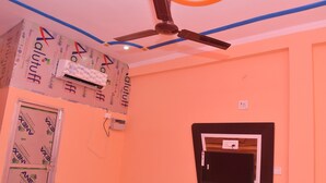 A room with a ceiling fan, an air conditioning unit, and a wall-mounted television. - Hotel Sahu Inn Ayodhya (Faizabad)