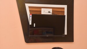 A wall-mounted television with a wooden panel and a power outlet. - Hotel Sahu Inn Ayodhya (Faizabad)