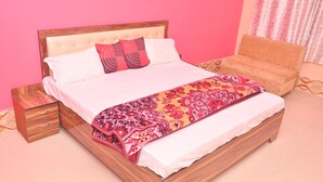 A bed with a wooden frame, a patterned blanket, and two pillows. - Hotel Sahu Inn Ayodhya (Faizabad)