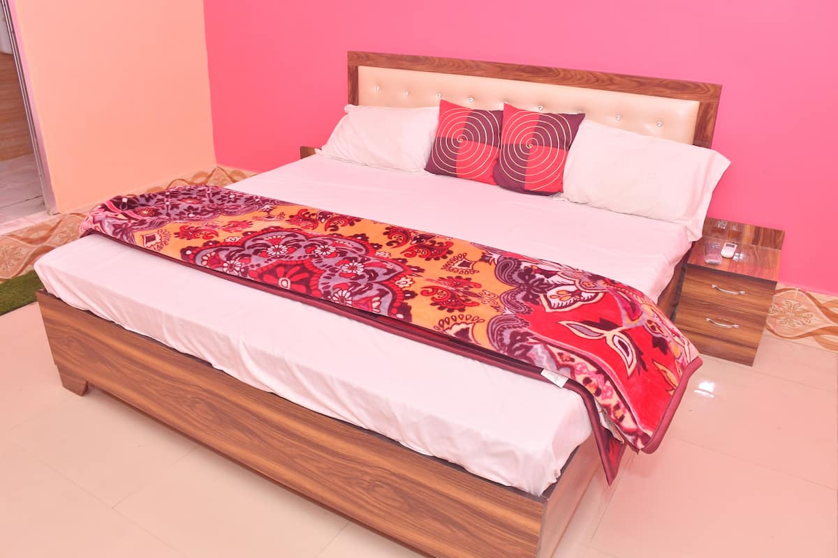 Una cama con un edredón estampado, almohadas blancas y un cabecero de madera.