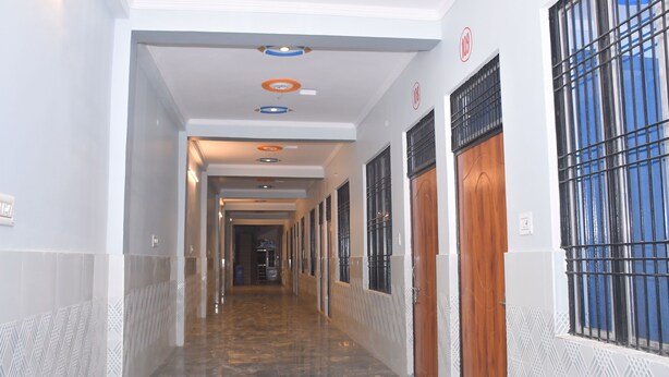 A hallway with patterned walls, a marble floor, and doors with metal bars. - Hotel Sahu Inn Ayodhya (Faizabad)