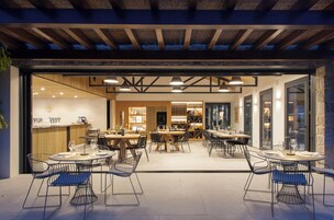 Un comedor interior con mesas y sillas, una recepción y una exhibición de vinos.