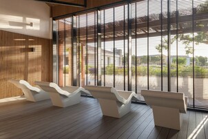Un área de estar moderna con suelo de madera y asientos blancos de diseño ondulado.