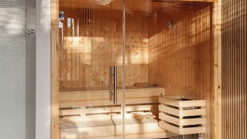A sauna with wooden walls and a glass door, featuring a bench and a small wooden cabinet.