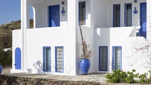 A white building with blue accents, including doors and windows, and a large blue pot on the ground. - Nataly's Apartment (Andros)