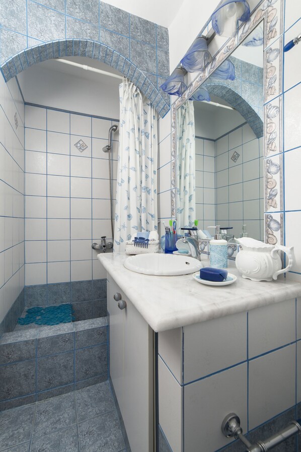 A bathroom with a shower, a sink, and a mirror. - Nataly's Apartment (Andros)