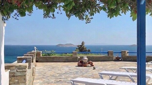 A stone patio with white lounge chairs and a view of the sea. - Nataly's Apartment (Andros)