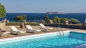 A swimming pool with lounge chairs and a view of the ocean. - Nataly's Apartment (Andros)