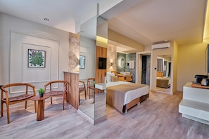 A modern hotel room with a bed, a desk, and two chairs. There is a mirror on the wall and a plant on the desk. - DER INN LARA (Antalya)