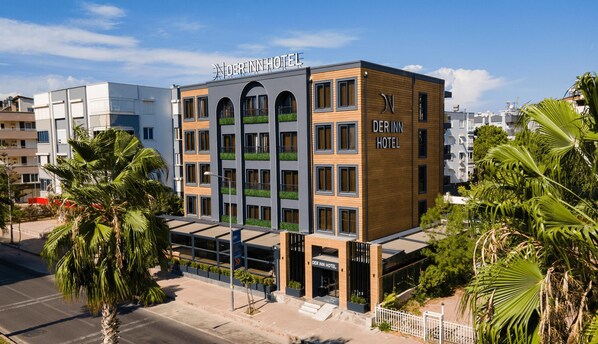 A modern hotel with a prominent sign, multiple floors, and a mix of glass and wood facade. - DER INN LARA (Antalya)
