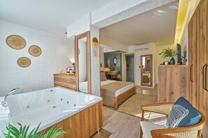 A modern bathroom with a large bathtub, wooden vanity, and decorative wall art. - DER INN LARA (Antalya)