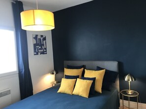 A bedroom with a bed, two bedside lamps, and a wall art piece.