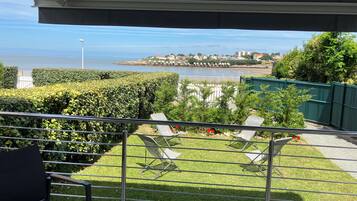 A balcony with a view of a coastal area, including a body of water and a distant shoreline with buildings.